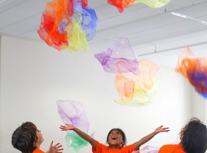 Kinder werfen bunte Tücher beim kreativen Kindertanz